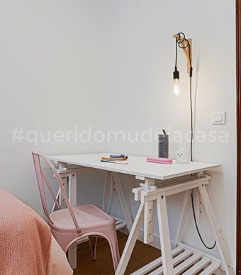 secretária feita com tampo de madeira e cavaletes pintados de branco e cadeira de metal cor de rosa